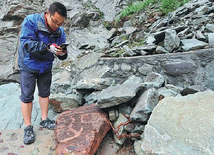 A staff member at the Helan Mountain Rock Paintings Conservation Park in the Ningxia Hui autonomous region checks rock carvings damaged by flooding this week. Wu Xiaoyu / For China Daily