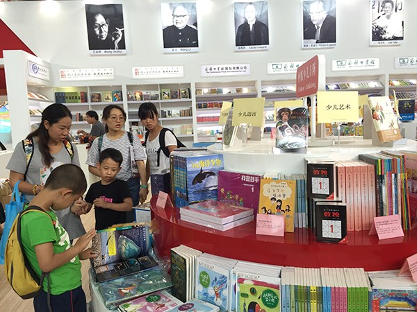 Children and parents reading books at the booth of the China Publishing Group on Aug 24. (Photo by Chen Yingqun/chinadaily.com.cn)