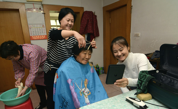Three volunteers give Ye Sufen, a 83-year-old who lives alone, a haircut at her home in Jinzhou, Liaoning province. (Photo by LI TIECHENG/CHINA DAILY)