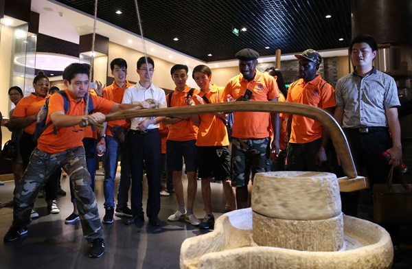International students from Southwest University in Chongqing learn how to use a traditional Chinese mill to produce flour at a museum in the city. (Photo by WANG ZHUANGFEI/CHINA DAILY)
