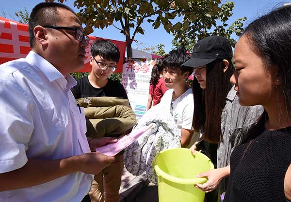 A worker from the Handan Branch of Agricultural Bank of China tells new students how to distinguish telecom fraud at Hebei University of Engineering on their first day at the school.(Hao Qunying/for China Daily)