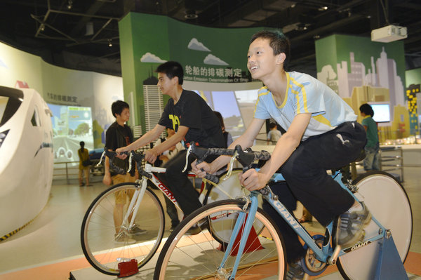 Visitors cycle to measure their carbon discharge at the Low-carbon City section of the museum. (Photo provided to China Daily)