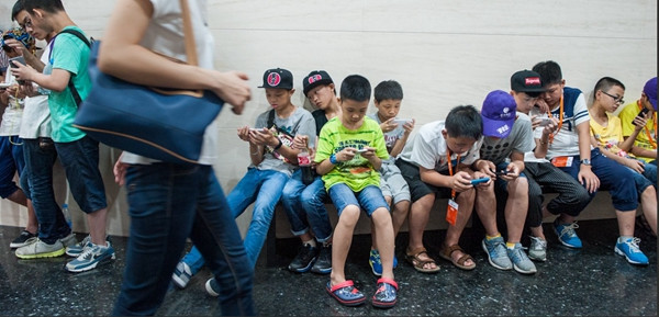 A group of primary school students play with their smartphones while visiting a museum in Beijing. (Wang Weiwei / For China Daily)