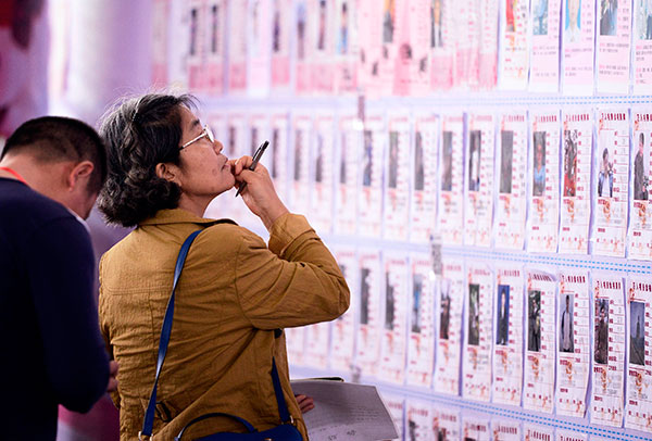 A woman looks for a suitable candidate for her unattached child at a matchmaking activity in Dongguan, Guangdong province.(Photo by AN DONG/CHINA DAILY)