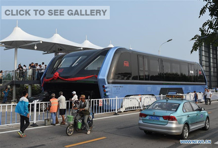 The transit elevated bus TEB-1 is on road test in Qinhuangdao, north China's Hebei Province, Aug. 2, 2016. China's home-made transit elevated bus, TEB-1, conducted a road test running Tuesday. The 22-meter-long, 7.8-meter-wide and 4.8-meter-high TEB-1 can carry up to 300 passengers. The passenger compartment of this futuristic public bus rises far above other vehicles on the road, allowing cars to pass underneath. (Xinhua/Luo Xiaoguang)