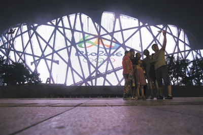 Visitors pose for a photo in front of Beijing's Bird's Nest. (Photo/The Beijing News) 