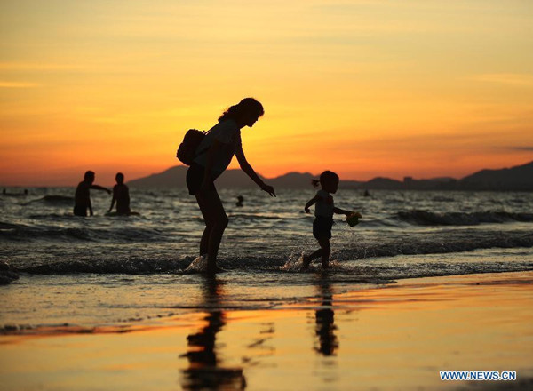 A mother plays with her child at the seashore in sunset in Sanya, south China' Hainan Province, September, 2015. (Photo: Xinhua/Chen Wenwu)
