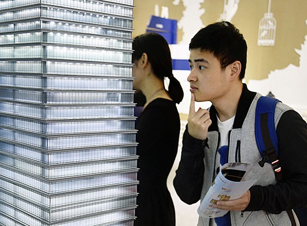 A resident looks at the model of a high-end residential building at an expo in Hangzhou, East China's Zhejiang province, May 13, 2016. (PROVIDED TO CHINA DAILY)
