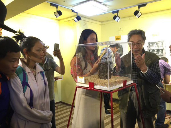 Yu Youxin, a prominent artist, briefs visitors about a tsa-tsa, or miniature figurine, exhibited on Barkor Street in Lhasa, Tibet autonomous region, August 14, 2016.(Photo by Palden Nyima/chinadaily.com.cn)