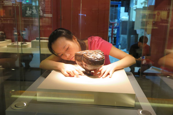 A worker arranges a lacquer bowl which will open to visitors in the Jinsha Site Museum in Chengdu, Sichuan province from August 20 to October 31.The bowl was used in the sacrificial ceremony more than 2,000 years ago (Photo by Huang Zhiling/chinadaily.com.cn)