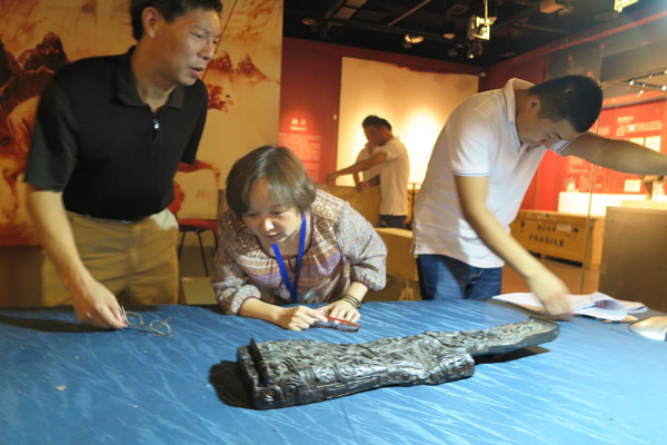 Archaeologists examine a musical instrument made of lacquer more than 2,000 years ago in the Jinsha Site Museum in Chengdu, Sichuan province. It will open to visitors in the museum from August 20 to October 31.(Photo by Huang Zhiling/chinadaily.com.cn)