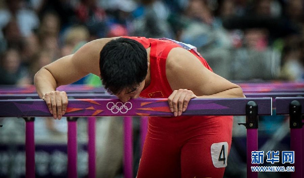 Liu Xiang kisses the hurdle after he hopped down the track to the finishing line in the heat of 110-meter hurdles in 2012 London Olympic Games, Aug 7. (Photo/Xinhua)