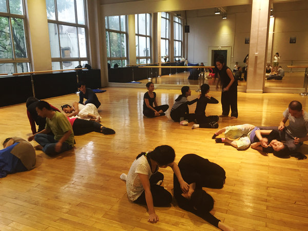 Students help each other to feel their spines at Lin's class, Beijing, Aug 18, 2016. (Photo by Li Hongrui/chinadaily.com)