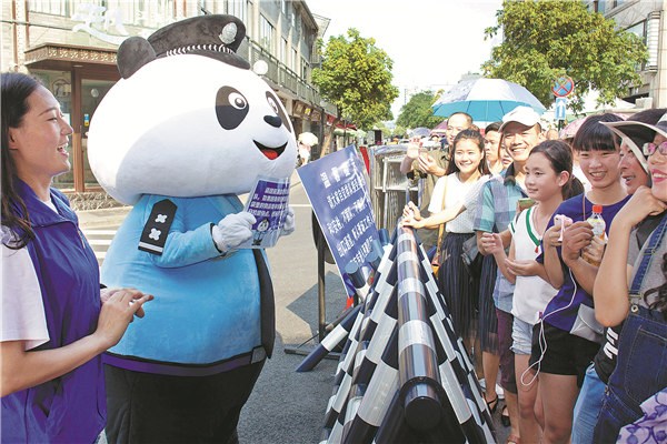 Shen Yijie,a junior at Zhejiang Police College, wears a cartoon panda costume while providing assistance to tourists lined up at the security check for admission to Hangzhous West Lake. The city has beefed up security ahead of the G20 summit. Gao Erqiang / China Daily