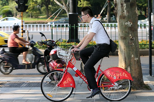A Hangzhou resident uses a public bike to commute. (Photo/China Daily)