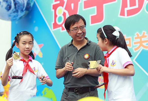 Pan Jianwei(center), chief quantum scientist at the Chinese Academy of Sciences (CAS), gives a gift to Students at Zhongguancun No1 Primary School in Beijing. (Photo by Zou Hong/chinadaily.com.cn)