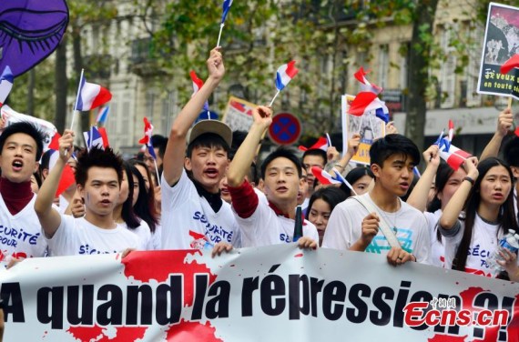 Demonstrators hold signs at a rally of the Chinese community to raise awareness about recent racists attacks in Paris, France, Sept. 4, 2016.(Photo: China News Service/Long Jianwu)