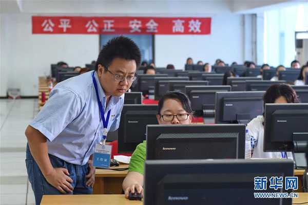 A teacher conducts a random check on an electronic exam paper at Jilin University, on June 14. (Photo by Zhang Nan/Xinhua)