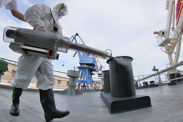 A quarantine officer sprays pesticide to kill mosquitoes on a cargo ship that arrived in Yantai, Shangdong province, in August, from Brazil, where the Zika virus has been detected. (Photo/Xinhua)