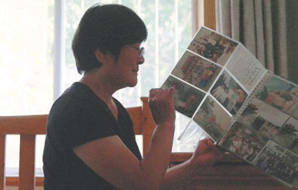 A retiree surnamed Liu, who thought of killing herself after a divorce, looks at her families' photos. (Photo by Zou Hong/China Daily)