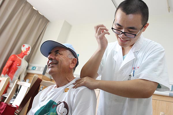 Peverani Givseppe, a member of a visiting delegation from San Marino, tries Chinese massage at Central Hospital of Shanghai Putuo District on Monday.(Photo by GAO ERQIANG/CHINA DAILY)