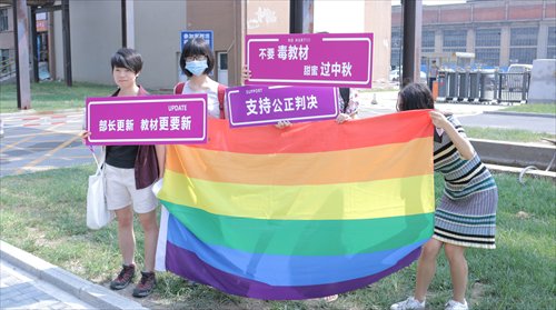 Qiu Bai, first from left, holds signs and the rainbow flag with friends outside the Beijing First Intermediate People's Court on Monday. (Photo/Courtesy of Qiu Bai)