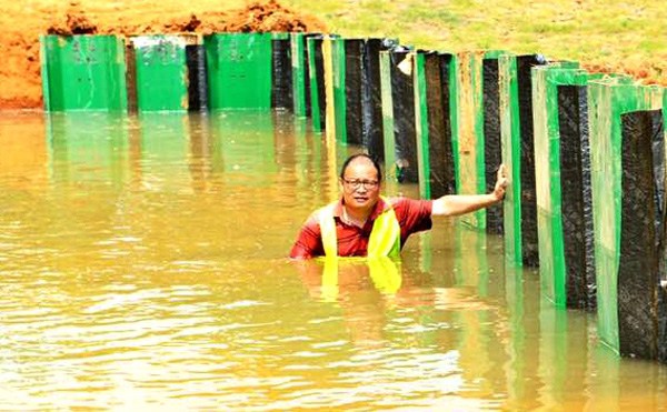 He Lijun stands in water during a test in Wuhan of the flood barrier shield he invented. (Provided To China Daily)