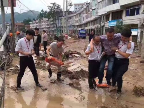 Bao Xuwei (R2), an education bureau official of Taishun county of east China's Zhejiang province, is carried by two insurance company employees while walking through a muddy puddle during the Typhon Meranti disaster relief in the county on Friday, Sept 16, 2016. (Photo/Wenzhou Metropolis Daily)