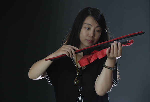 A woman plays a violin made by Qin.(Photo by Liu Jiaoqing/China Daily)