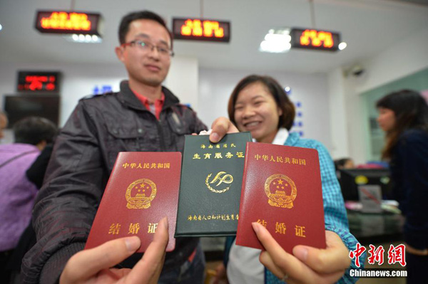 A couple holding Marriage Certificates (red) and Childbirth Certificate (green). Photo/Chinanews.com