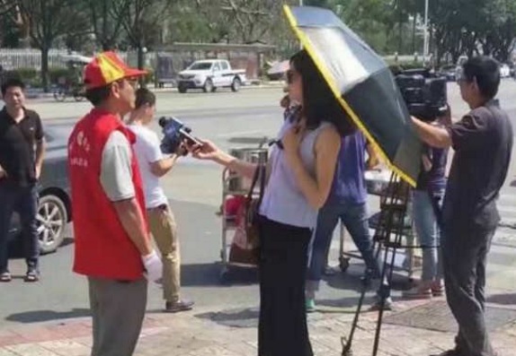 A female reporter holds an umbrella while reporting on disaster relief