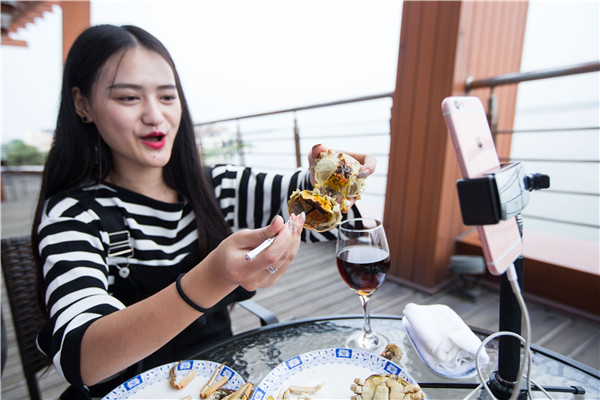 A social media anchorwoman broadcasts live her first taste of the crabs on the side of Yangcheng Lake on Friday. (Photo:China Daily/Xu Kangping)