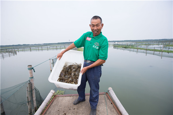 A farmer holds a box of newly harvested crabs at Yangcheng Lake in Suzhou, Jiangsu province, on Friday.(Photo:China Daily/Xu Kangping)