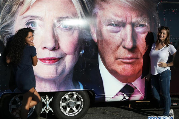 Supporters pose for photos with Hillary Clinton and Donald Trump posters at Hofstra University in New York, the United States on Sept. 26, 2016. The first of three presidential debates between the Democratic and Republican nominees, Hillary Clinton and Donald Trump, will be held Monday at Hofstra University in New York. (Xinhua/Qin Lang)