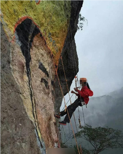 A woman climbs on a cliff to make a portrait painting for the man she loves. (Photo/Qianjiang Evening News)