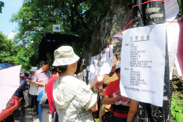 Parents read posters strung up on a line between two light poles next to the main entrance of the Wansong Shuyuan in Hangzhou. (Photo by Xing Yi/China Daily)