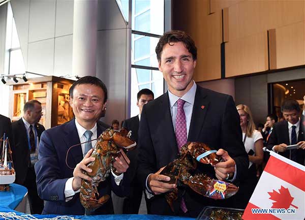 Jack Ma, executive chairman of Alibaba Group, and Canadian Prime Minister Justin Trudeau grab lobsters imported from Canada at the online giant's headquarters in Hangzhou, Zhejiang province, on Saturday. (Photo/Xinhua)