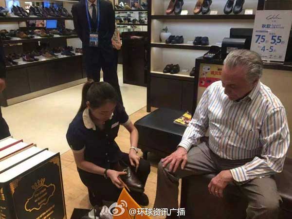 A shop assistant helps Temer try on a pair of shoes. (Photo/Sina Weibo)