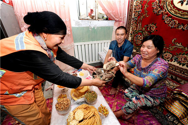 A resident of Urumqi, capital of the Xinjiang Uygur autonomous region, invites a visitor to try mutton during the Eid al-Adha Festival on Monday. (Photo by ZHANG WANDE/FOR CHINA DAILY)