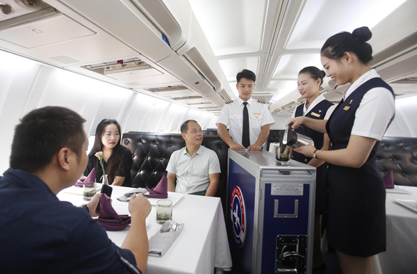 Servers dressed as flight crew members pour drinks for customers in the airplane-themed restaurant. (Photo by Chen Zhuo/For China Daily)