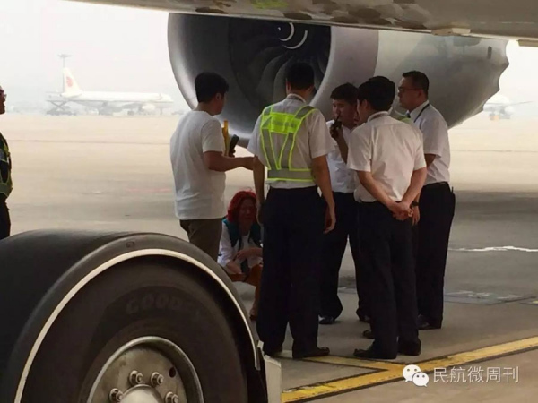 A woman tries to persuade staff of the Beijing Capital International Airport to let her board a plane by squatting on the ground of the airport runway because she missed her flight on Sept 14, 2016. (Photo from WeChat)