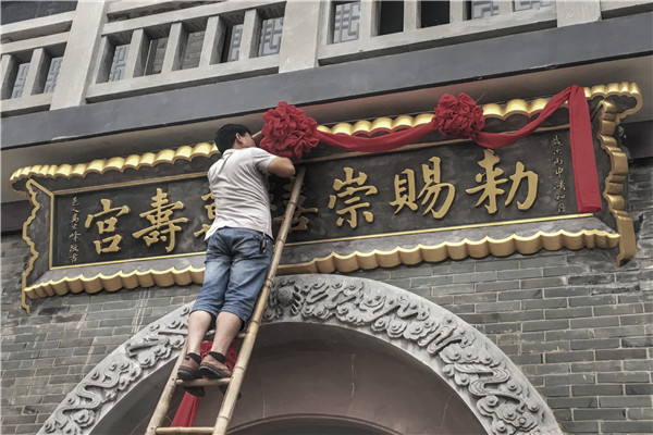 A worker puts a ribbon on the Chongxi Wanshou Temple before its inauguration. (Photo provided to China Daily)