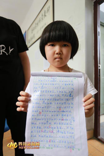 A third grader, born with aplastic anemia, holds her story up in Suining, Southwest China's Sichuan province. (File photo/newssc.org)