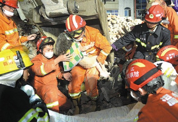 Firefighters rescue a 6-year-old girl from the rubble after four buildings collapsed in Wenzhou, Zhejiang province, on Monday. (Photo/China Daily)