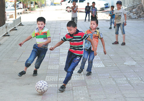 Children play soccer on a sidewalk in Kashgar in the Xinjiang Uygur autonomous region. (Photo/Xinhua)