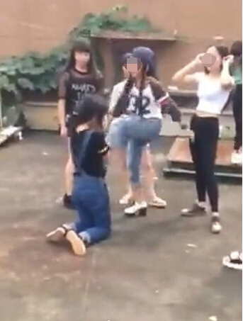 A number of girls beat and kick a fellow female student who kneels down on the ground in Yongxin county, Jiangxi province. (Photo/ Weibo)