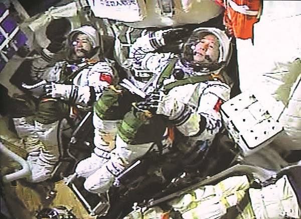 Astronauts Jing Haipeng (right) and Chen Dong salute inside the spacecraft at the moment of launching on Monday. (Photo/Xinhua)