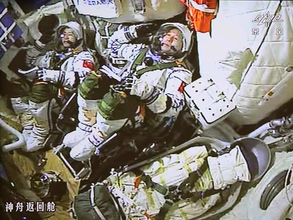 Astronauts Jing Haipeng (right) and Chen Dong salute inside the spacecraft at the moment of launching on Monday. (Photo/Xinhua)