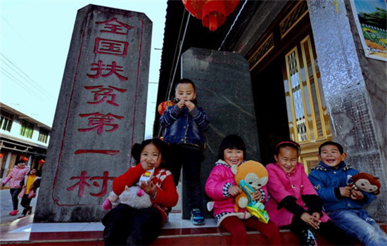 Children of Se ethnic group sit in front of a monument that reads China's No. 1 Poverty Relief Village at Chixi Village, Panxi town, Fuding city in East China's Fujian province, Feb 14. The village has shaken off poverty thanks to assistance from Party and government officials at all levels over the past 30 years. (Photo/Xinhua)