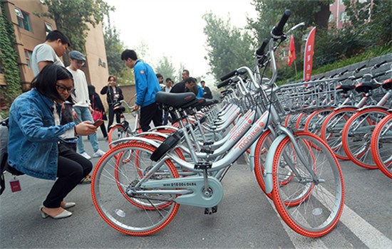 A reporter uses her cellphone to scan the QR code on a mobike in Beijing on Wednesday. (Photo by Zou Hong/China Daily)